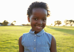 African elementary school girl smiling in a park, close up